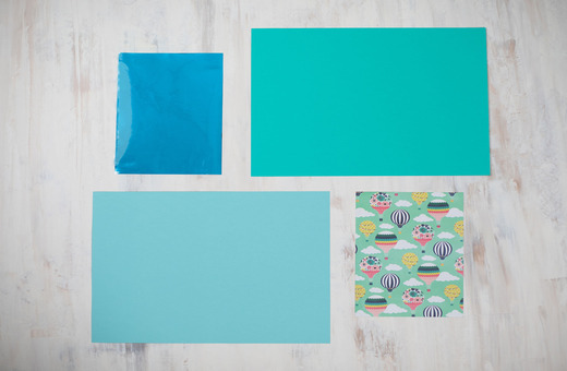 Four pieces of paper arranged on a light wooden surface: 