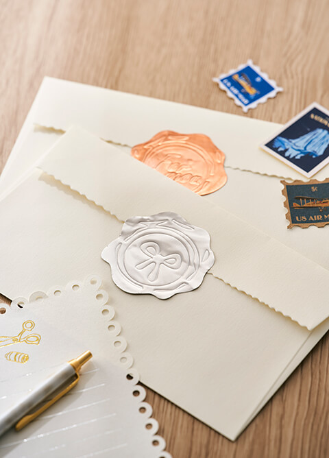 Two cream-colored envelopes sealed with decorative wax seals