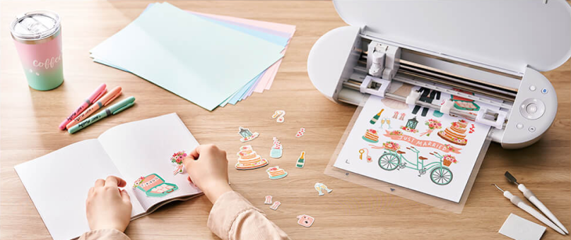 cutting machine in front of a computer monitor displaying a colorful floral design